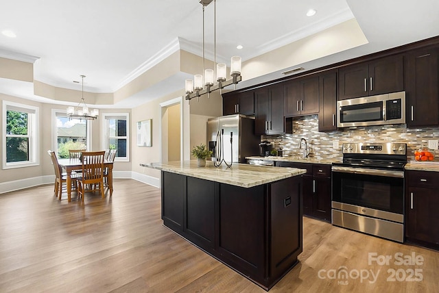 1311 Sunnys Halo Ln, Waxhaw, NC 28173 - kitchen featuring appliances with stainless steel finishes, a raised ceiling, light wood-style flooring, decorative backsplash, and ornamental molding