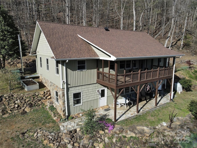 back of house featuring a shingled roof, a patio, and a wooden deck