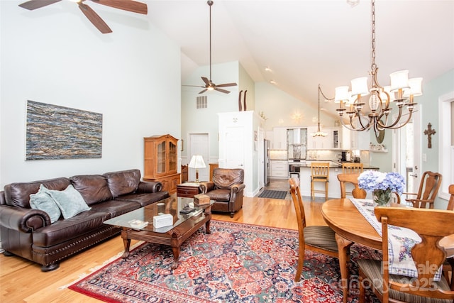 living room featuring ceiling fan, a chandelier, light wood-style floors, and high vaulted ceiling