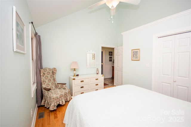 bedroom featuring wood finished floors, a closet, ceiling fan, and high vaulted ceiling