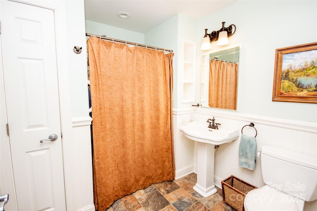 full bath with stone finish flooring and toilet