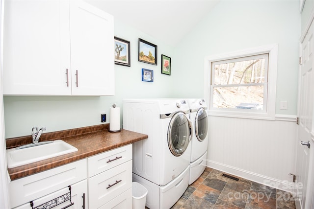 laundry room with separate washer and dryer, cabinet space, and stone finish floors