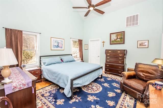 bedroom with light wood-type flooring, a ceiling fan, and high vaulted ceiling