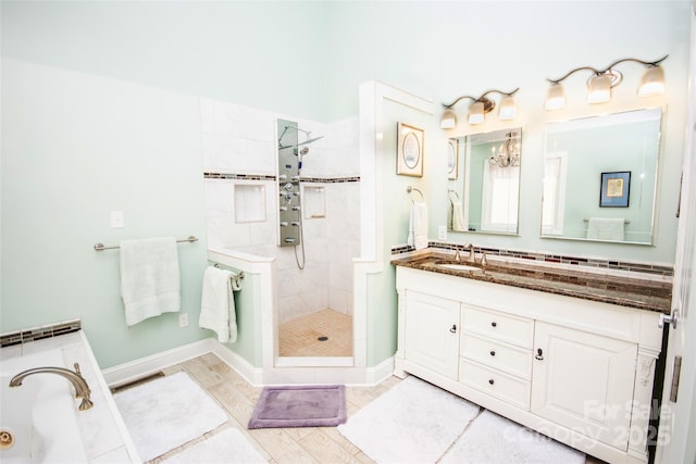 bathroom featuring a tile shower, vanity, a garden tub, and baseboards