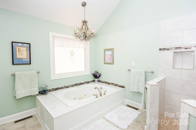 bathroom featuring a chandelier, a jetted tub, baseboards, vaulted ceiling, and wood finished floors