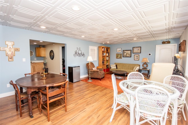 dining space featuring an ornate ceiling, light wood-style floors, recessed lighting, and baseboards