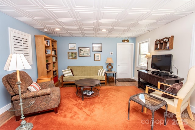 living room featuring wood finished floors, baseboards, an ornate ceiling, and recessed lighting