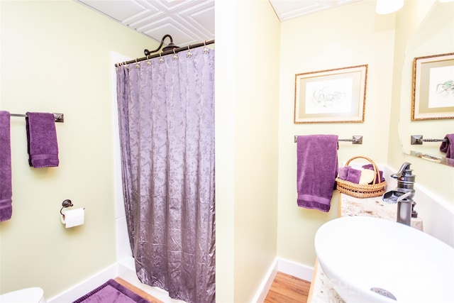 full bath with a sink, toilet, a shower with curtain, and baseboards
