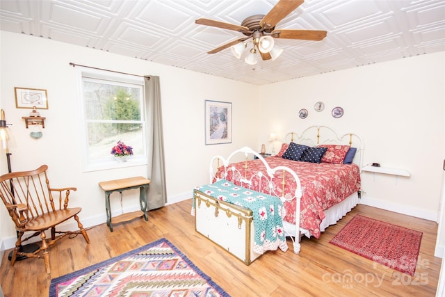 bedroom featuring an ornate ceiling, wood finished floors, baseboards, and ceiling fan