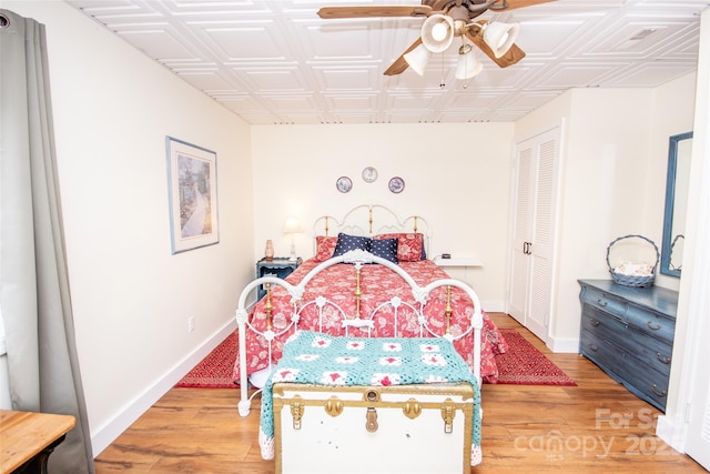 bedroom featuring an ornate ceiling, light wood-style floors, baseboards, a closet, and a ceiling fan