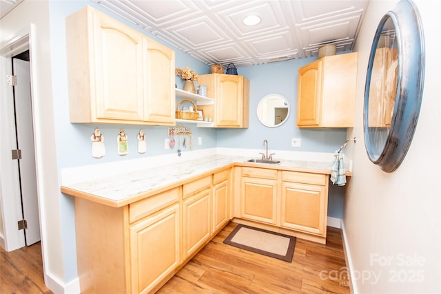 kitchen with a sink, light brown cabinetry, light wood-style flooring, an ornate ceiling, and open shelves