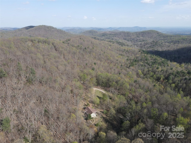 aerial view of property's location featuring a forest and a mountainous background