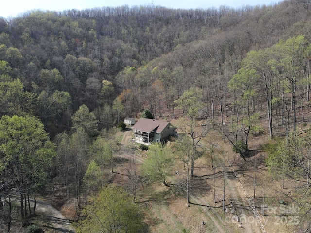 aerial view of property and surrounding area featuring a heavily wooded area
