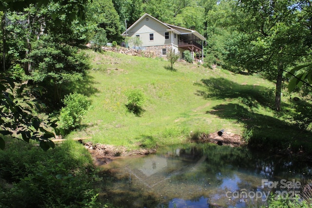 view of grassy yard featuring stairway, a wooded view, and a water view