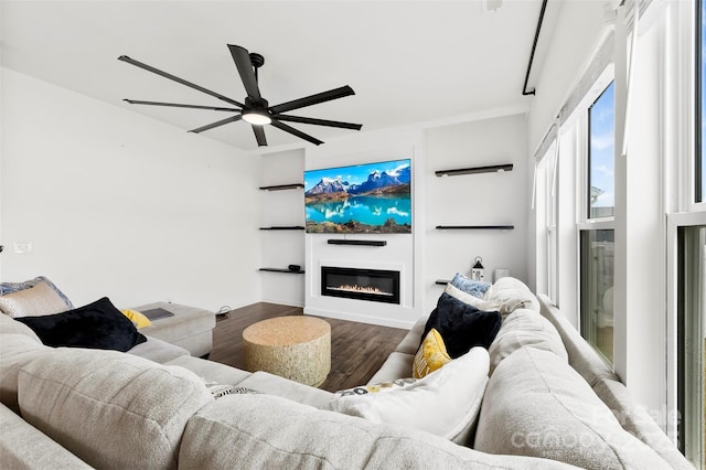 living area with a ceiling fan, a glass covered fireplace, and wood finished floors