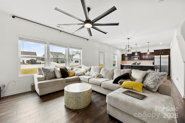 living area with baseboards, a ceiling fan, and dark wood finished floors