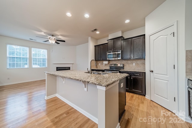 9001 Lanark Ln, Indian Land, SC 29707 - kitchen with appliances with stainless steel finishes, a sink, ceiling fan, light wood-style floors, and tasteful backsplash
