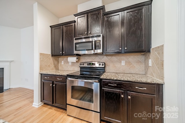 9001 Lanark Ln, Indian Land, SC 29707 - kitchen featuring stainless steel appliances, light wood-style flooring, light stone counters, and tasteful backsplash