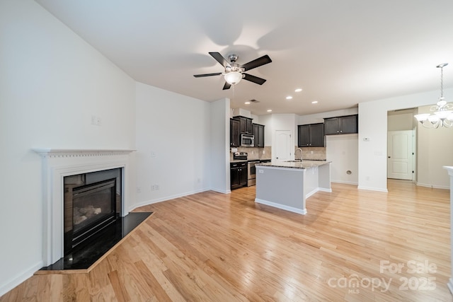 9001 Lanark Ln, Indian Land, SC 29707 - kitchen featuring appliances with stainless steel finishes, open floor plan, light wood-style floors, decorative backsplash, and ceiling fan
