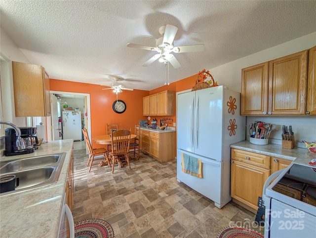 kitchen with ceiling fan, a sink, light countertops, and white appliances