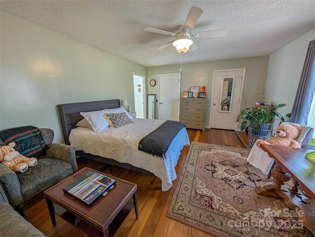 bedroom with hardwood / wood-style floors, a ceiling fan, and a textured ceiling