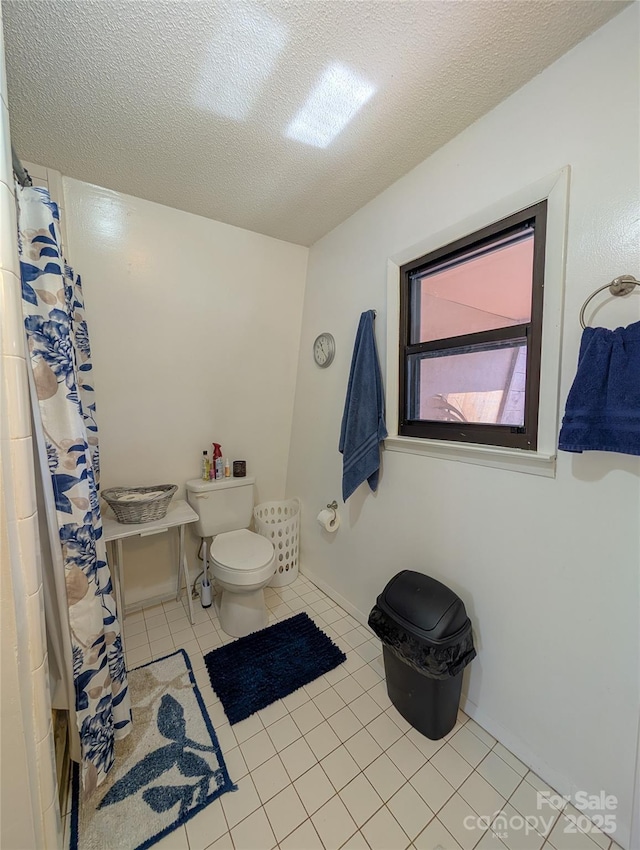 bathroom with a shower with curtain, toilet, tile patterned flooring, and a textured ceiling