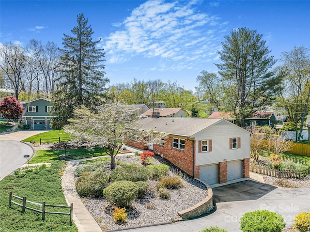 view of property exterior with brick siding, an attached garage, fence, and driveway