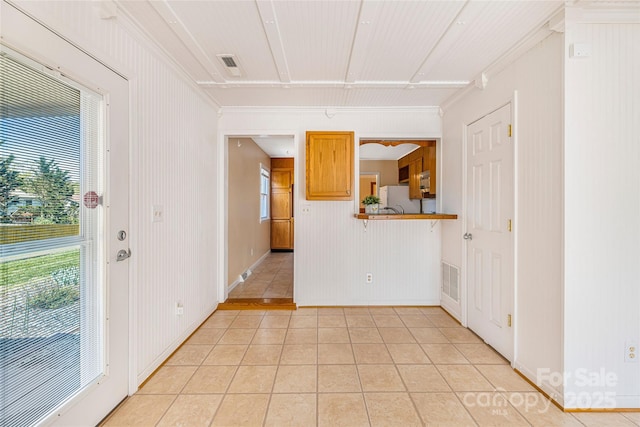 interior space featuring crown molding, visible vents, baseboards, and light tile patterned floors