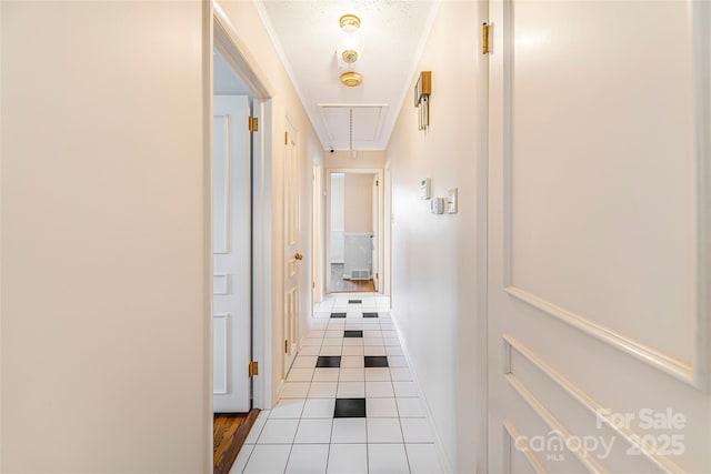 hallway featuring baseboards, attic access, and tile patterned flooring