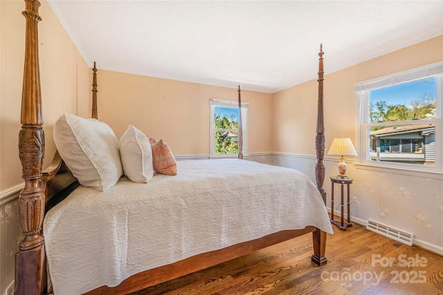 bedroom featuring visible vents, baseboards, and wood finished floors