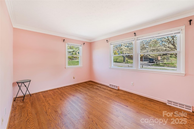 unfurnished room with visible vents, baseboards, crown molding, and wood finished floors