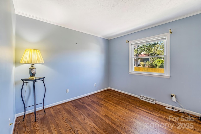 spare room with dark wood-style floors, baseboards, ornamental molding, and visible vents