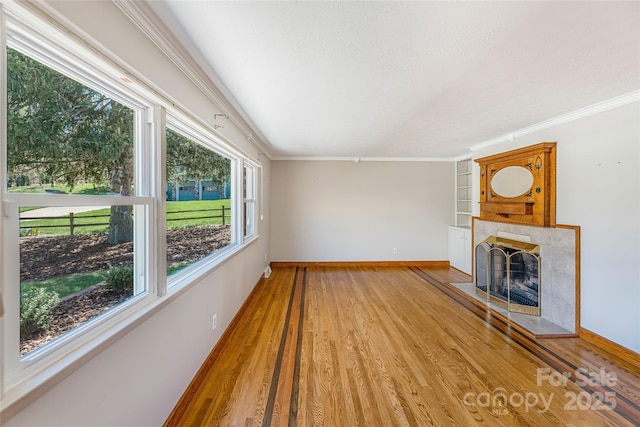 unfurnished living room with light wood-type flooring, a fireplace, baseboards, and ornamental molding