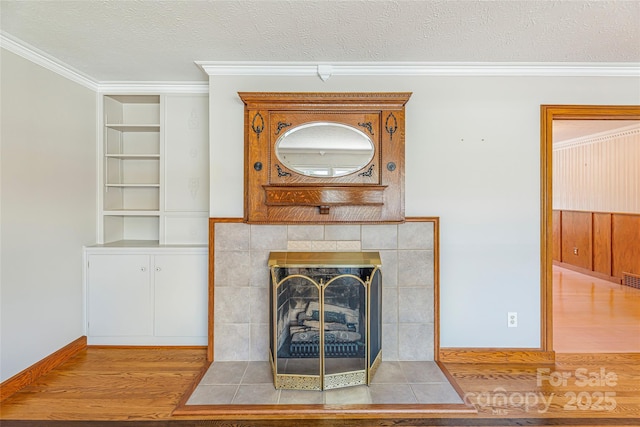 details featuring built in features, a fireplace, a textured ceiling, crown molding, and wood finished floors