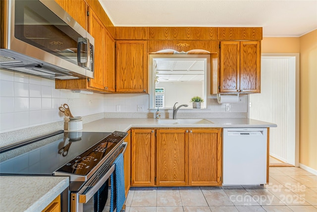 kitchen with a sink, light countertops, brown cabinets, stainless steel appliances, and decorative backsplash