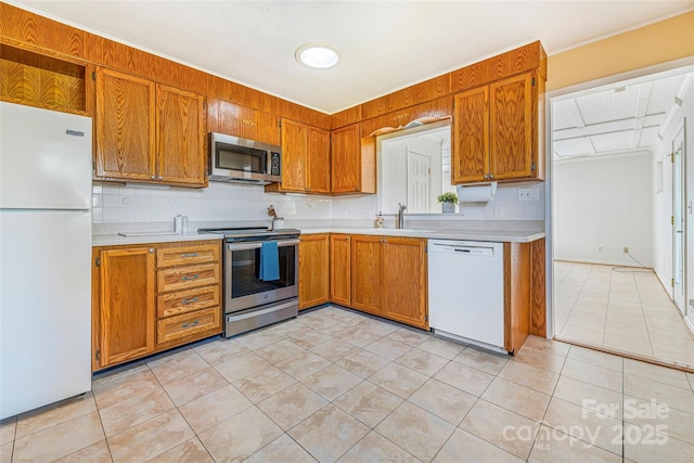 kitchen featuring brown cabinets, appliances with stainless steel finishes, light tile patterned floors, and light countertops