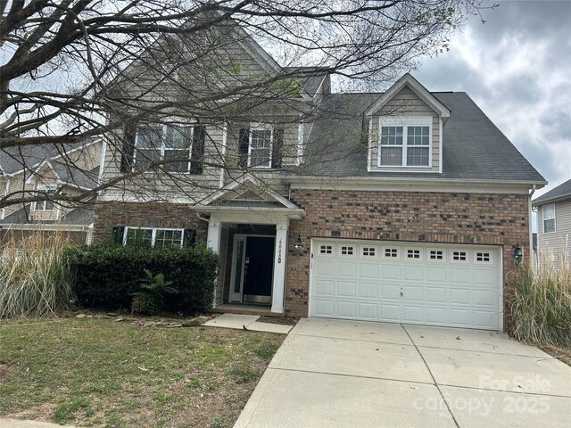 traditional-style home with a garage, driveway, and brick siding