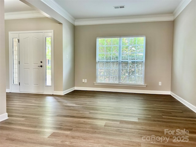 foyer entrance with baseboards, ornamental molding, wood finished floors, and visible vents