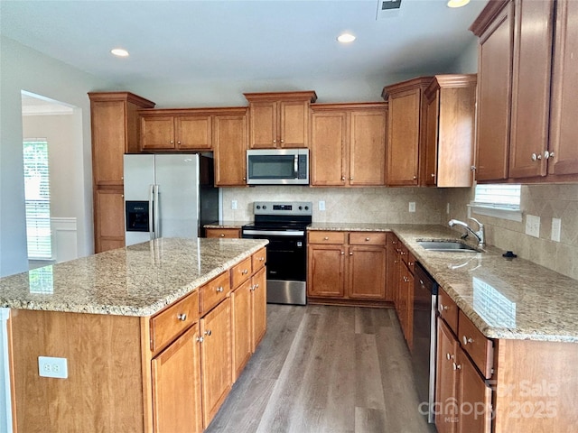kitchen with appliances with stainless steel finishes, a wealth of natural light, a sink, and light wood-style floors