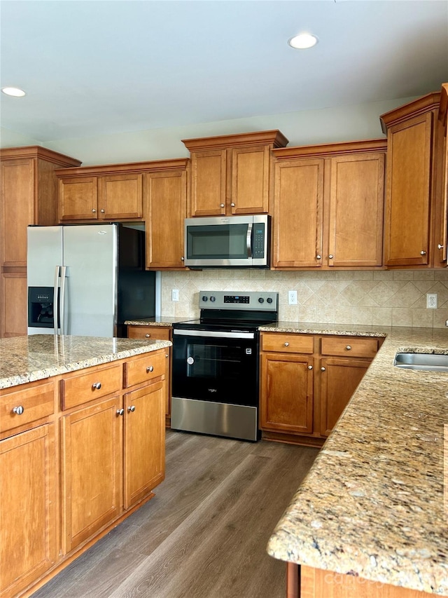 kitchen featuring recessed lighting, wood finished floors, brown cabinets, and stainless steel appliances