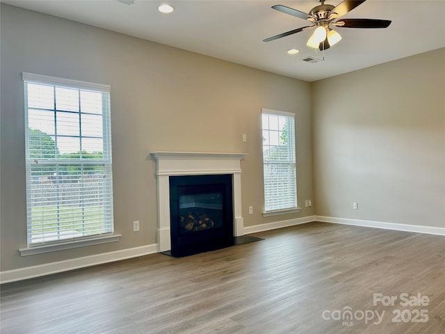unfurnished living room with baseboards, ceiling fan, wood finished floors, and visible vents