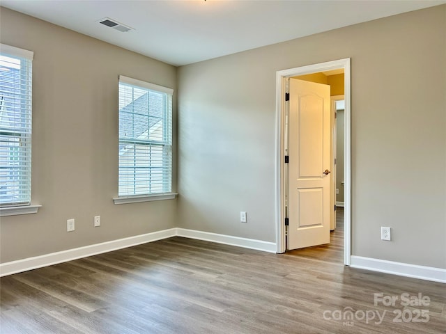 unfurnished room featuring baseboards, wood finished floors, and visible vents