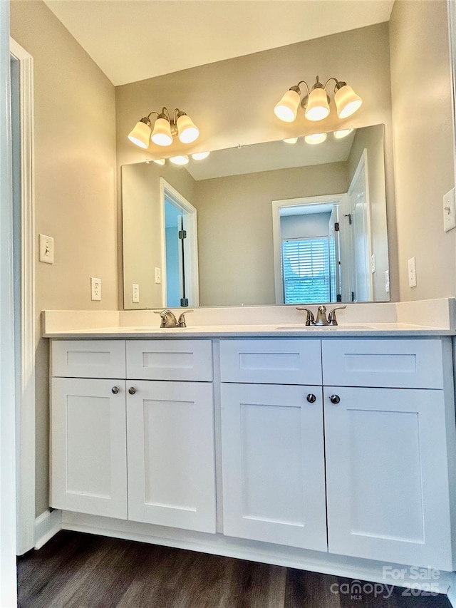 full bathroom featuring double vanity, a sink, and wood finished floors