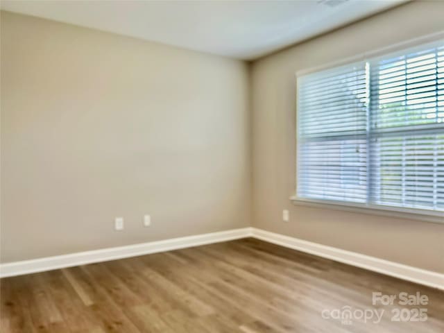 spare room with baseboards and wood finished floors