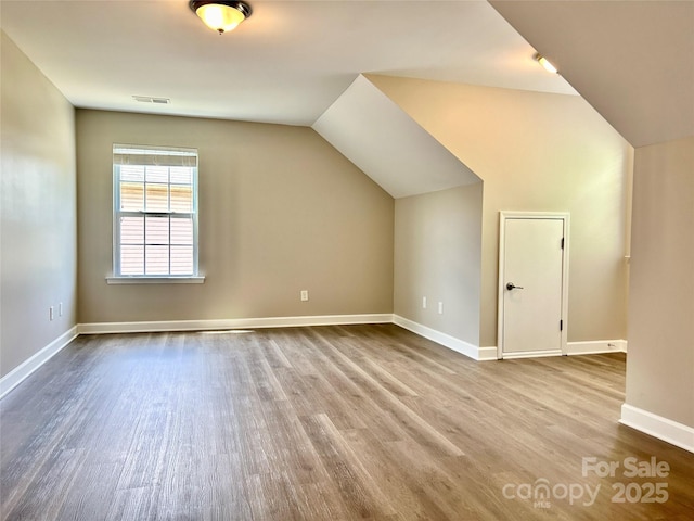 bonus room with visible vents, baseboards, lofted ceiling, and wood finished floors
