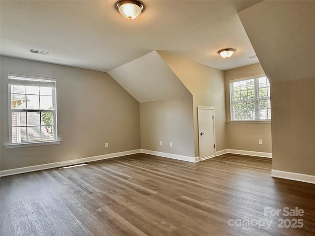 bonus room featuring visible vents, baseboards, lofted ceiling, and dark wood-style floors