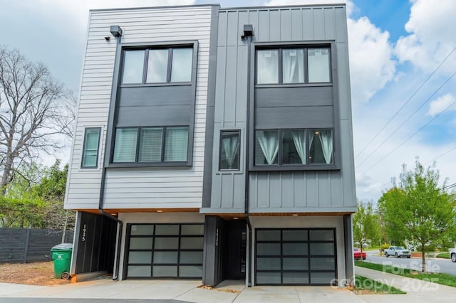contemporary house with an attached garage, fence, and board and batten siding