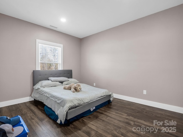 bedroom with baseboards, wood finished floors, and visible vents