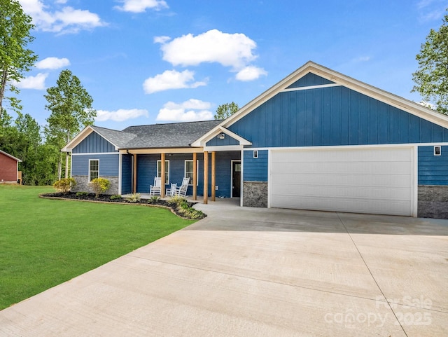 view of front facade featuring an attached garage, stone siding, a porch, a front yard, and driveway
