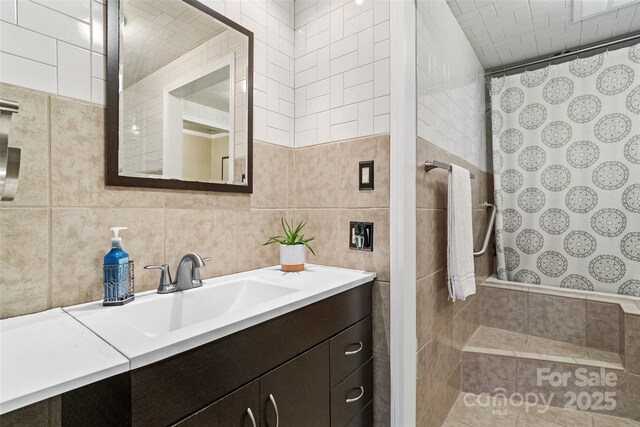 full bath with vanity, tiled shower, tile walls, and visible vents